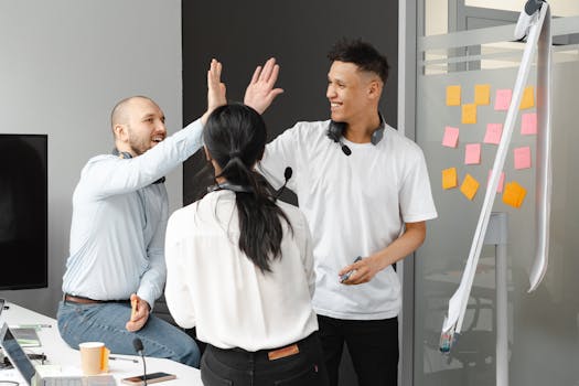 A cheerful team of professionals high-fiving during a collaborative meeting in an office.