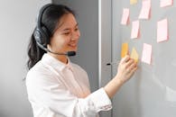Smiling Woman Writing on a Sticky Note