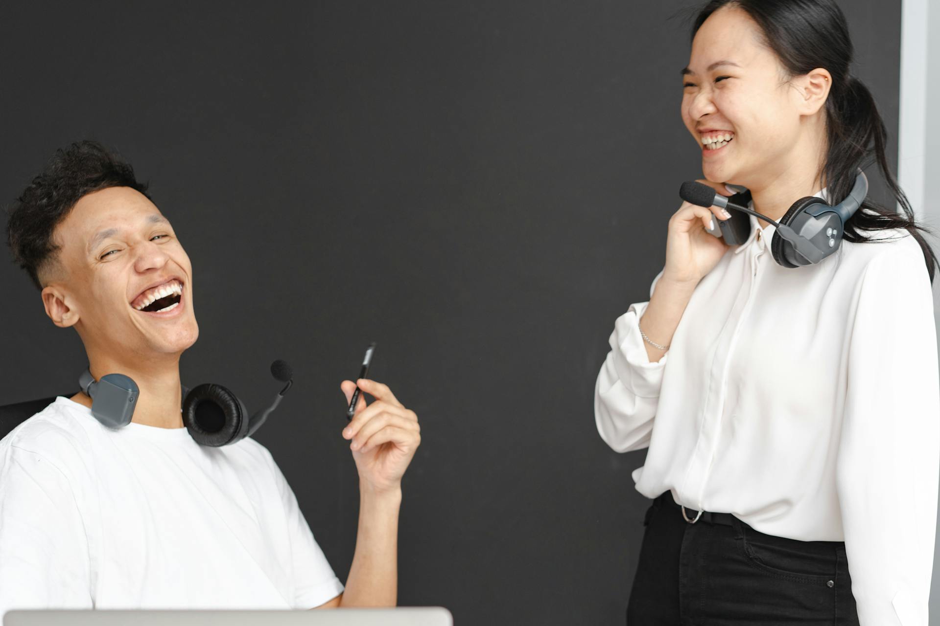 Happy customer service agents laughing and engaging at the office with headsets.