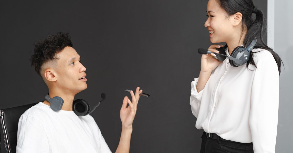 Two colleagues with headsets chat in a modern office setting, emphasizing teamwork and communication.