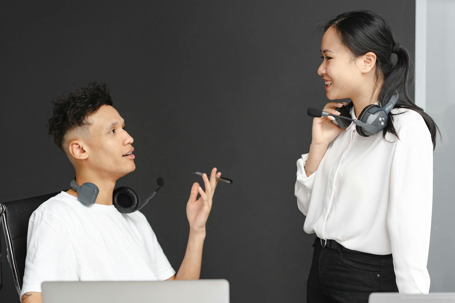 Two colleagues with headsets chat in a modern office setting, emphasizing teamwork and communication.