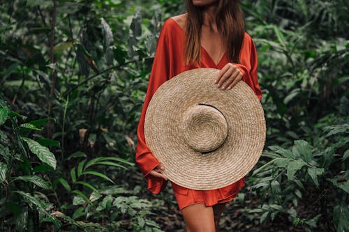 Woman in Red Dress Holding a Large Sun Hat