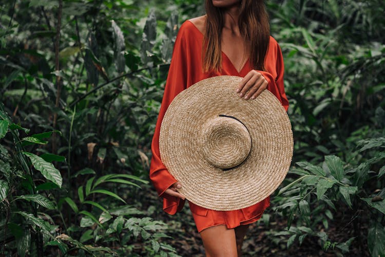 Woman In Red Dress Holding A Large Sun Hat