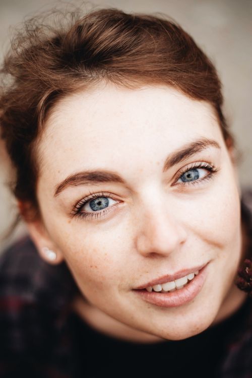 Free Portrait of young female with freckles and dark hair with gray eyes looking at camera in light place Stock Photo