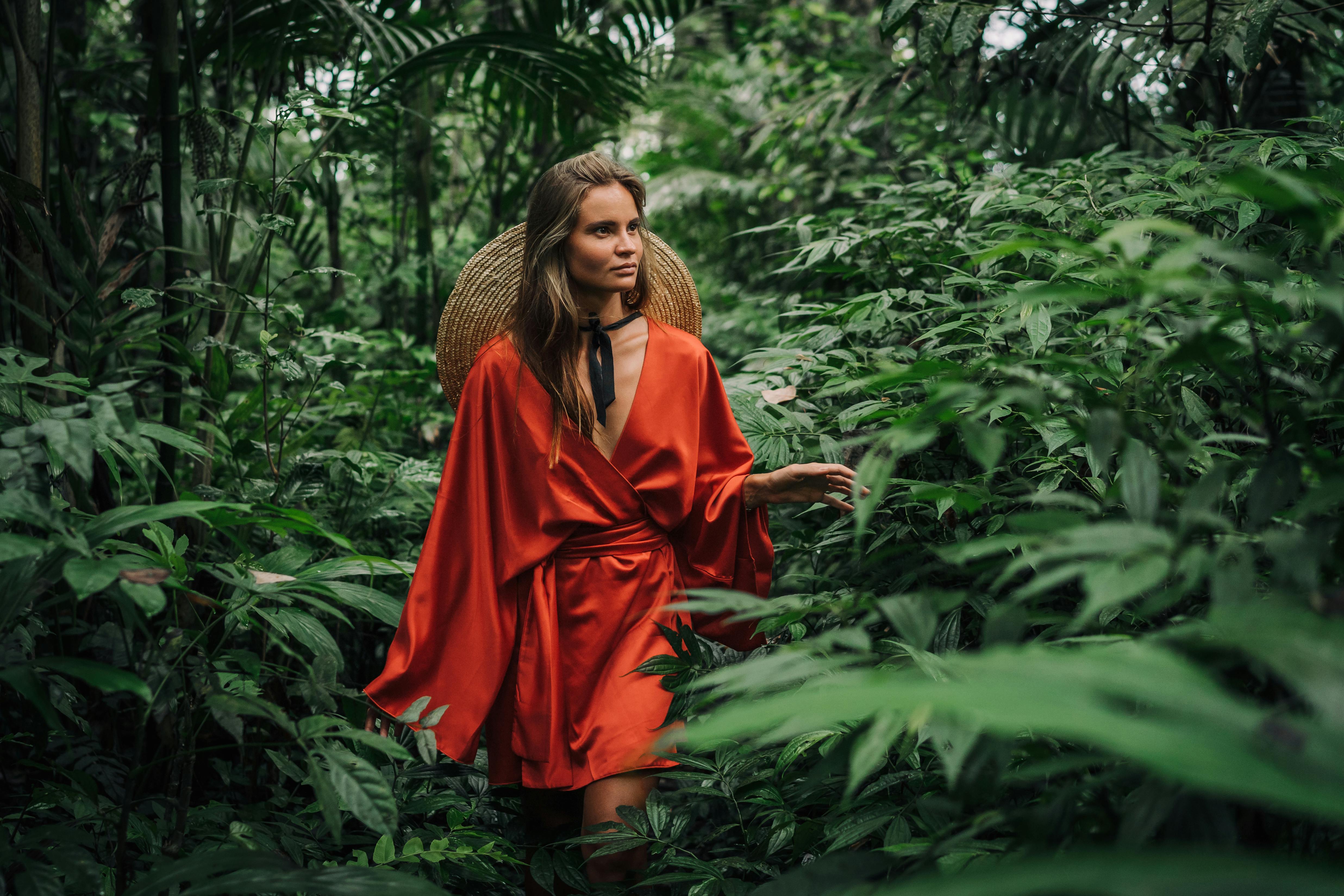 Woman in a Red Silk Dress Looking at Green Plants  Free Stock Photo