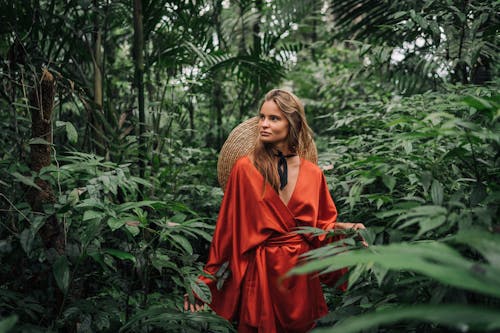 Woman in Red Silk Robe Standing Beside Green Plants