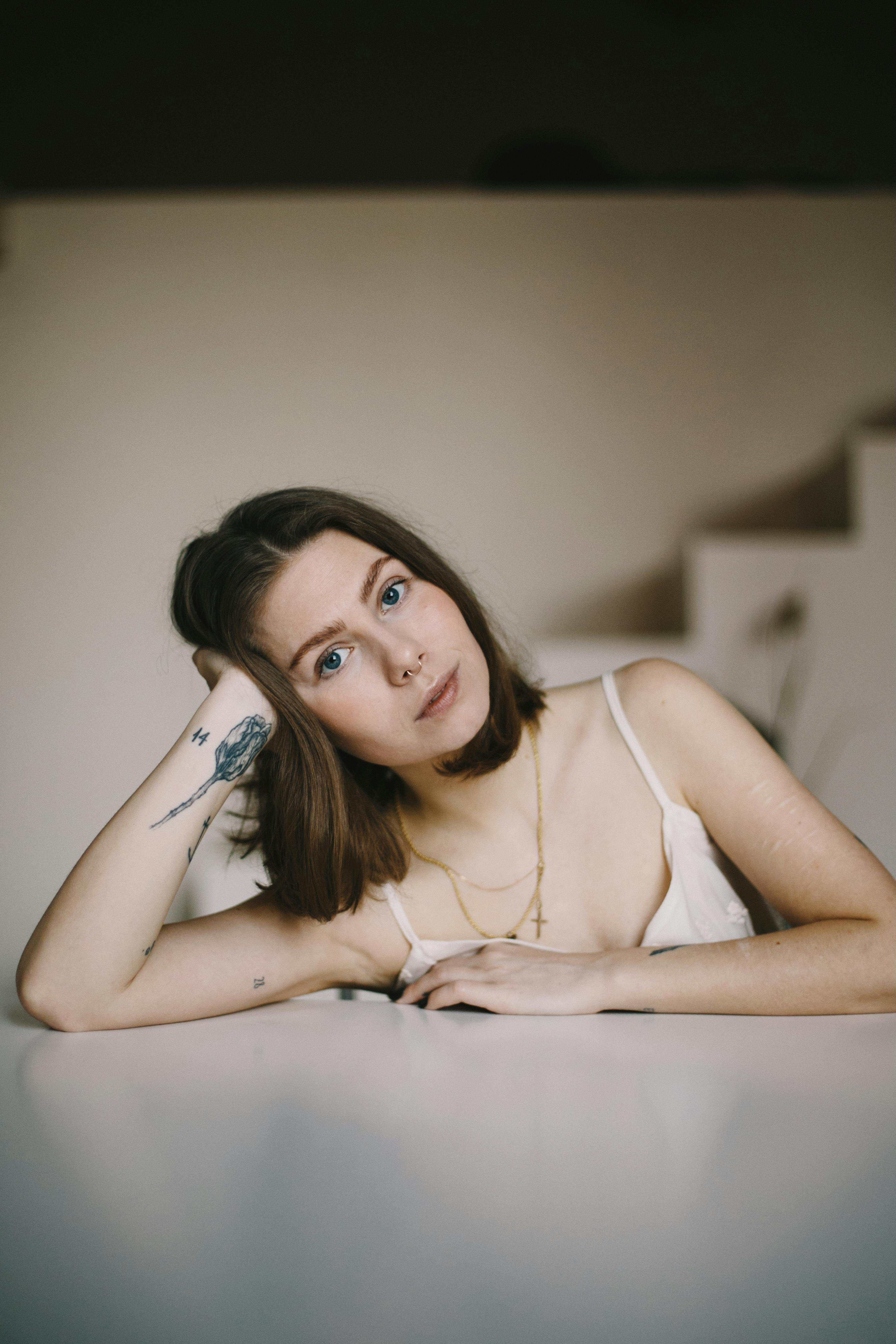 一幅现代肖像，以纹身的女人为特色，摆出休闲的姿势，提供时尚和现代的外观