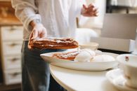 Faceless woman near plate with eclair and zephyr on table