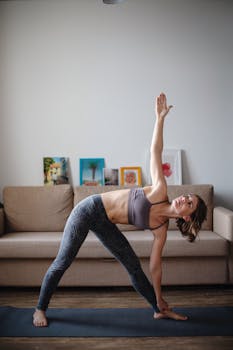 Woman performing yoga on mat indoors, showcasing flexibility and balance in a peaceful setting.