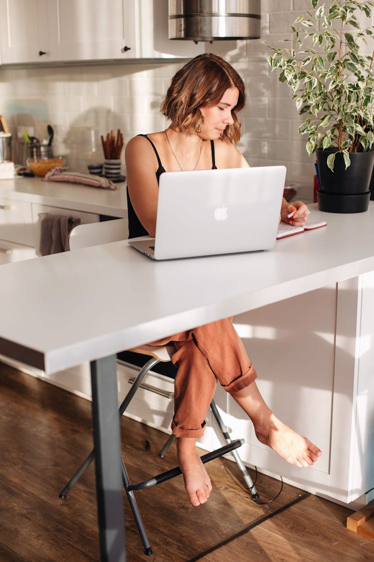 Woman Sitting By The Table Using A Macbook