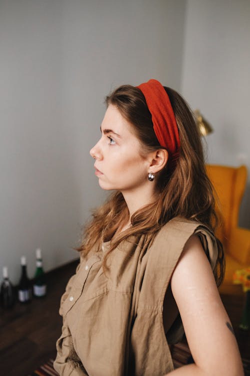 Side view of emotionless female with long brown hair looking away in blurred room