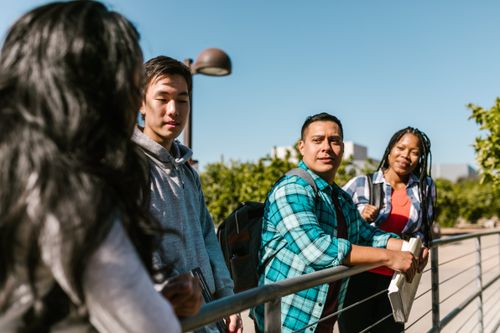Free Group of diverse students engaging in conversation outdoors at college. Stock Photo