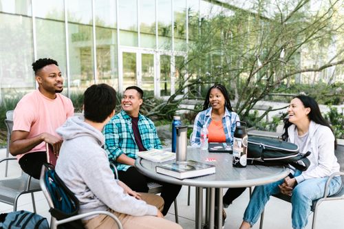 Free University students studying together outside at a campus table. Stock Photo
