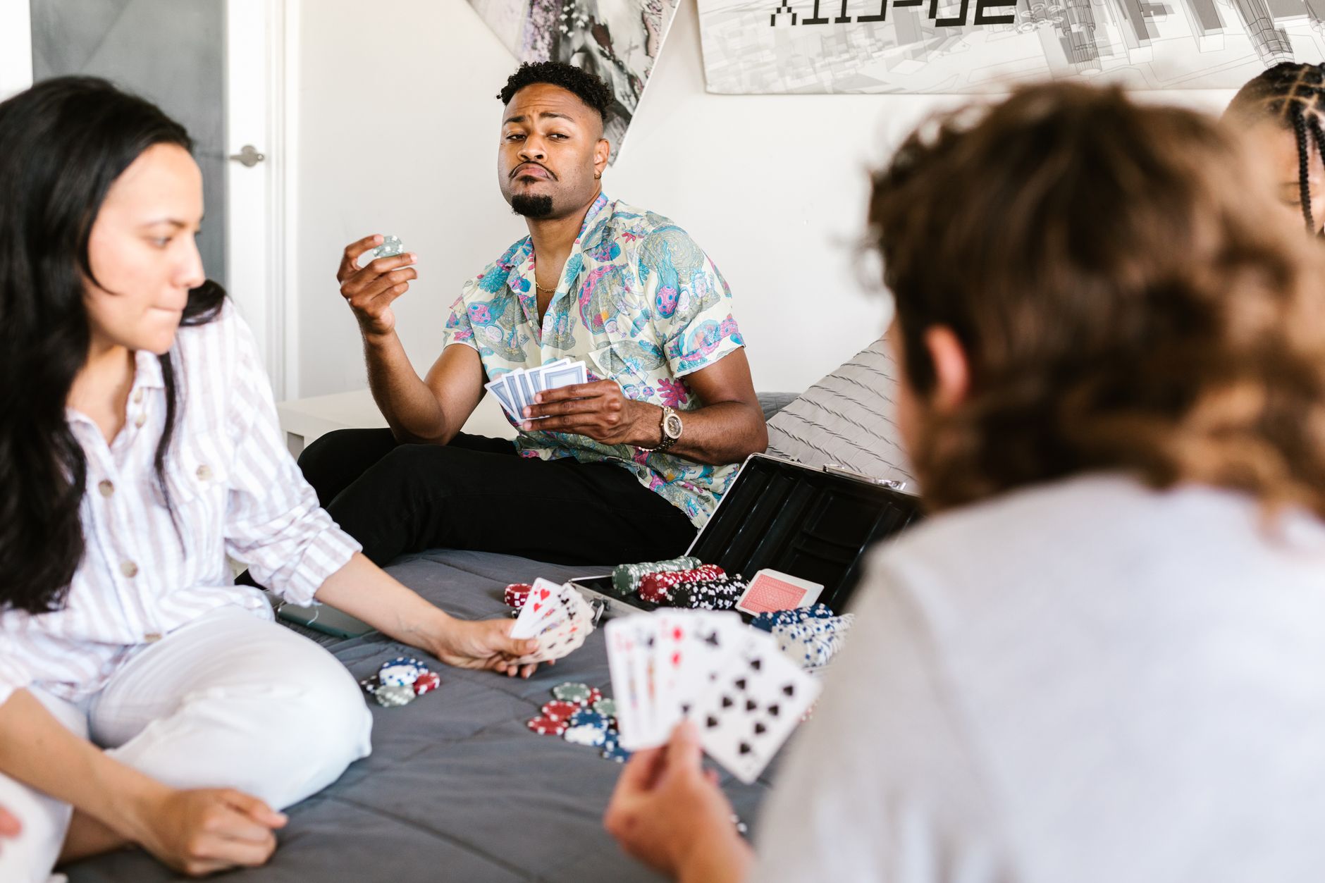 Group of college students playing poker in a cozy dormitory setting.