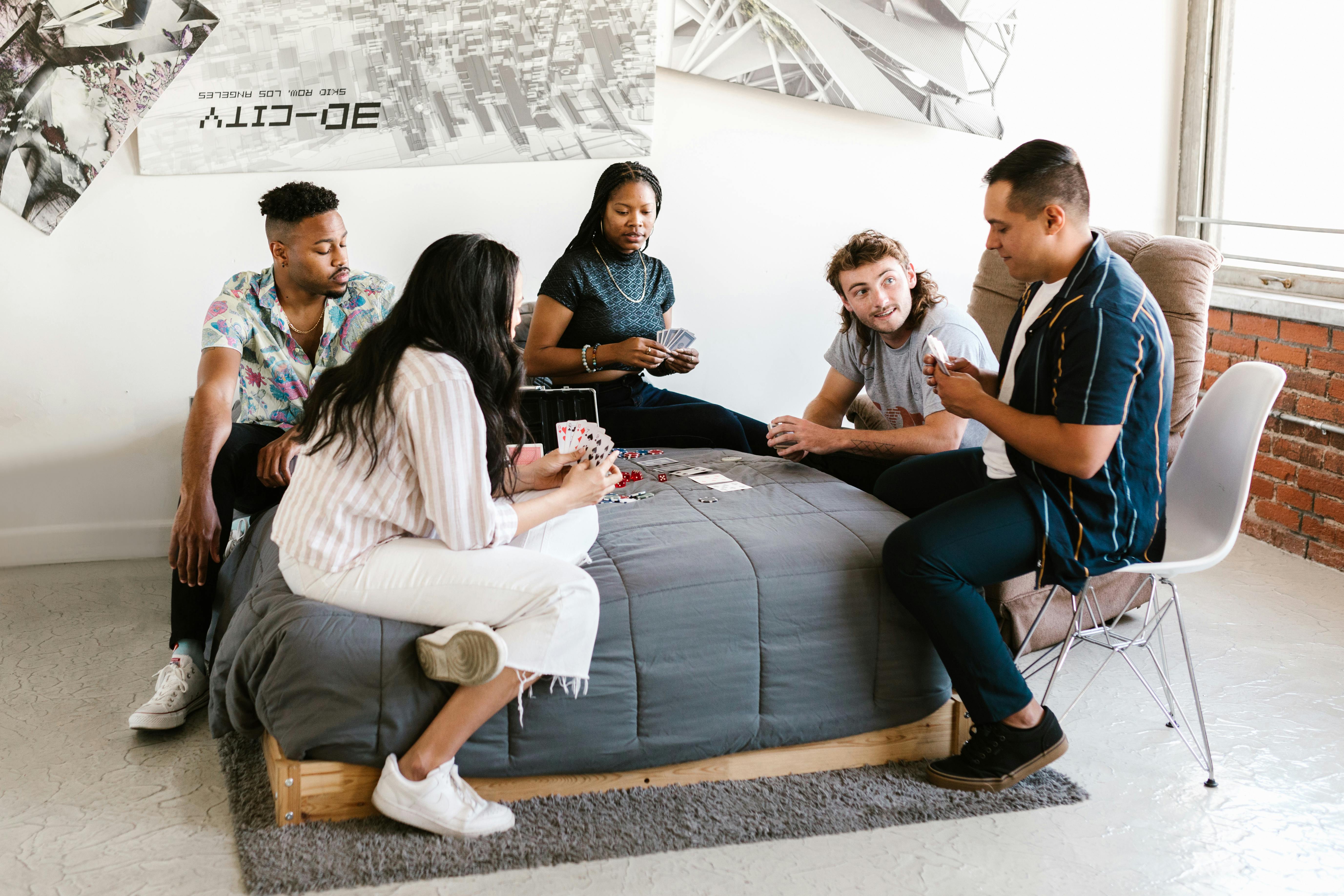 group of people sitting on gray bed while playing poker