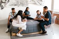 Group of People Sitting on Gray Bed While Playing Poker