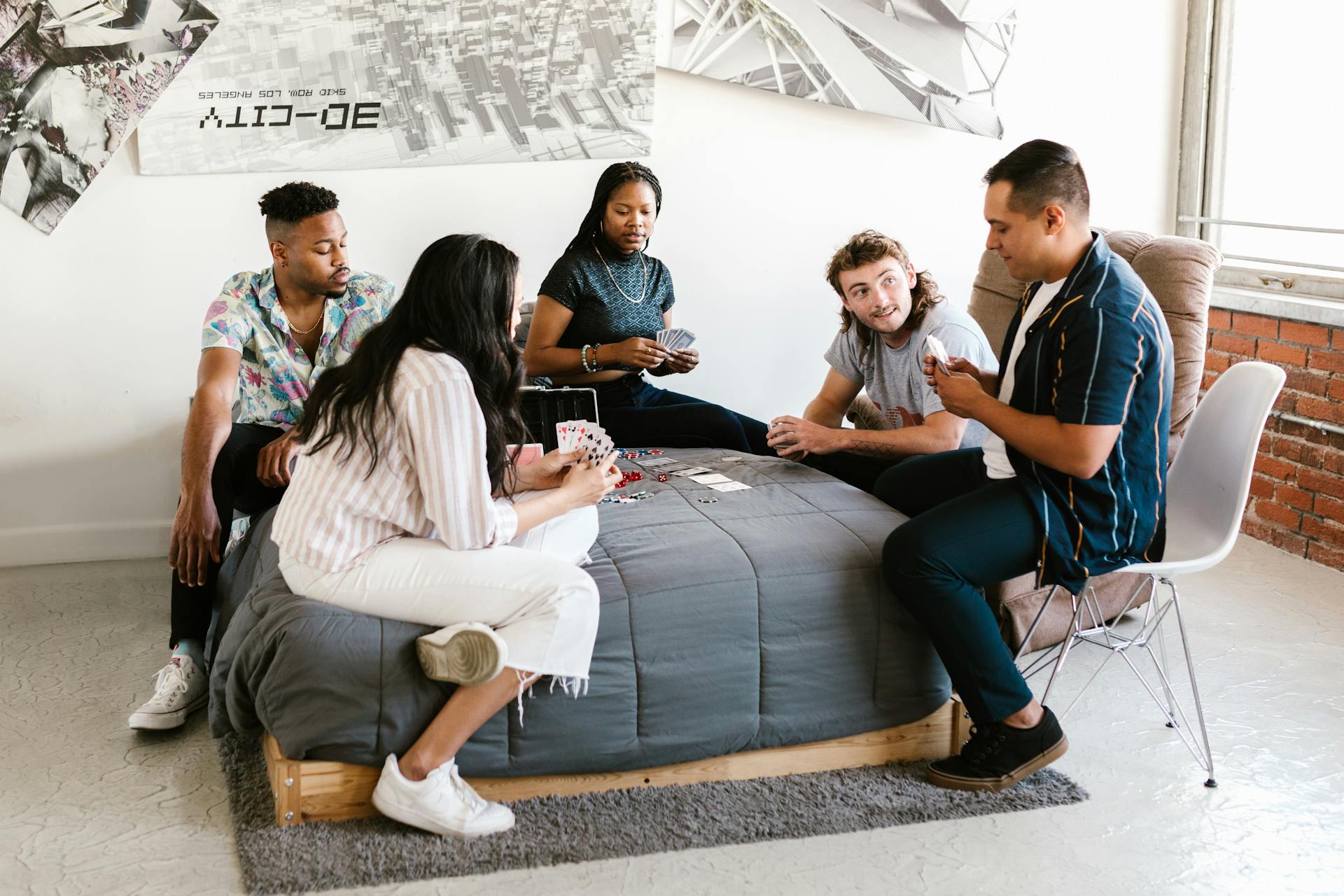 Group of college students enjoying a card game in a cozy dorm room setting.