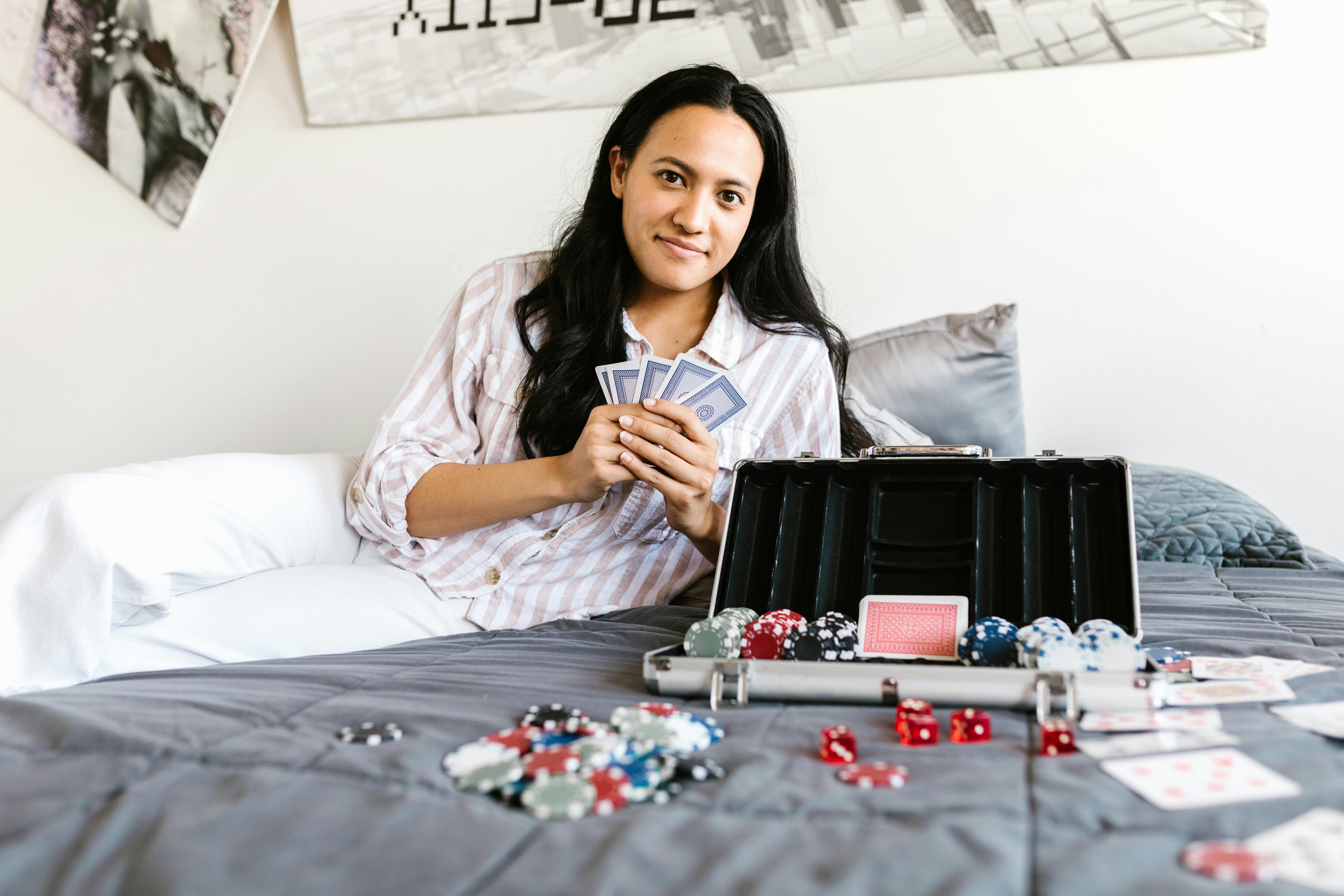 a woman sitting on the bed with poker cards and chips