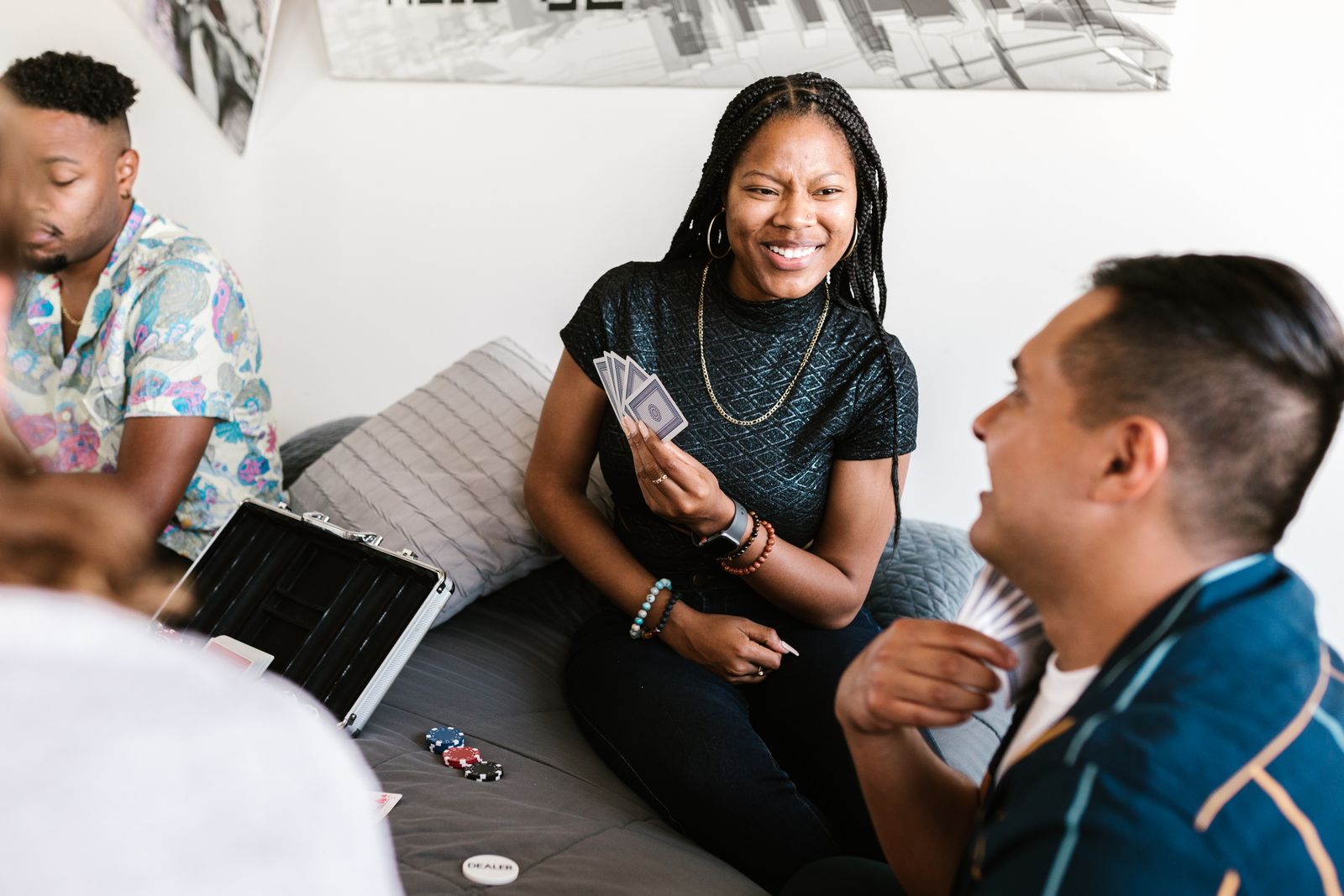 Friends laughing while playing a simple card game indoors.