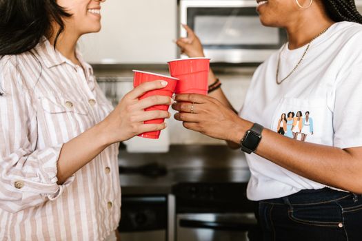 Women toasting with red cups in a casual indoor setting, enjoying time together.