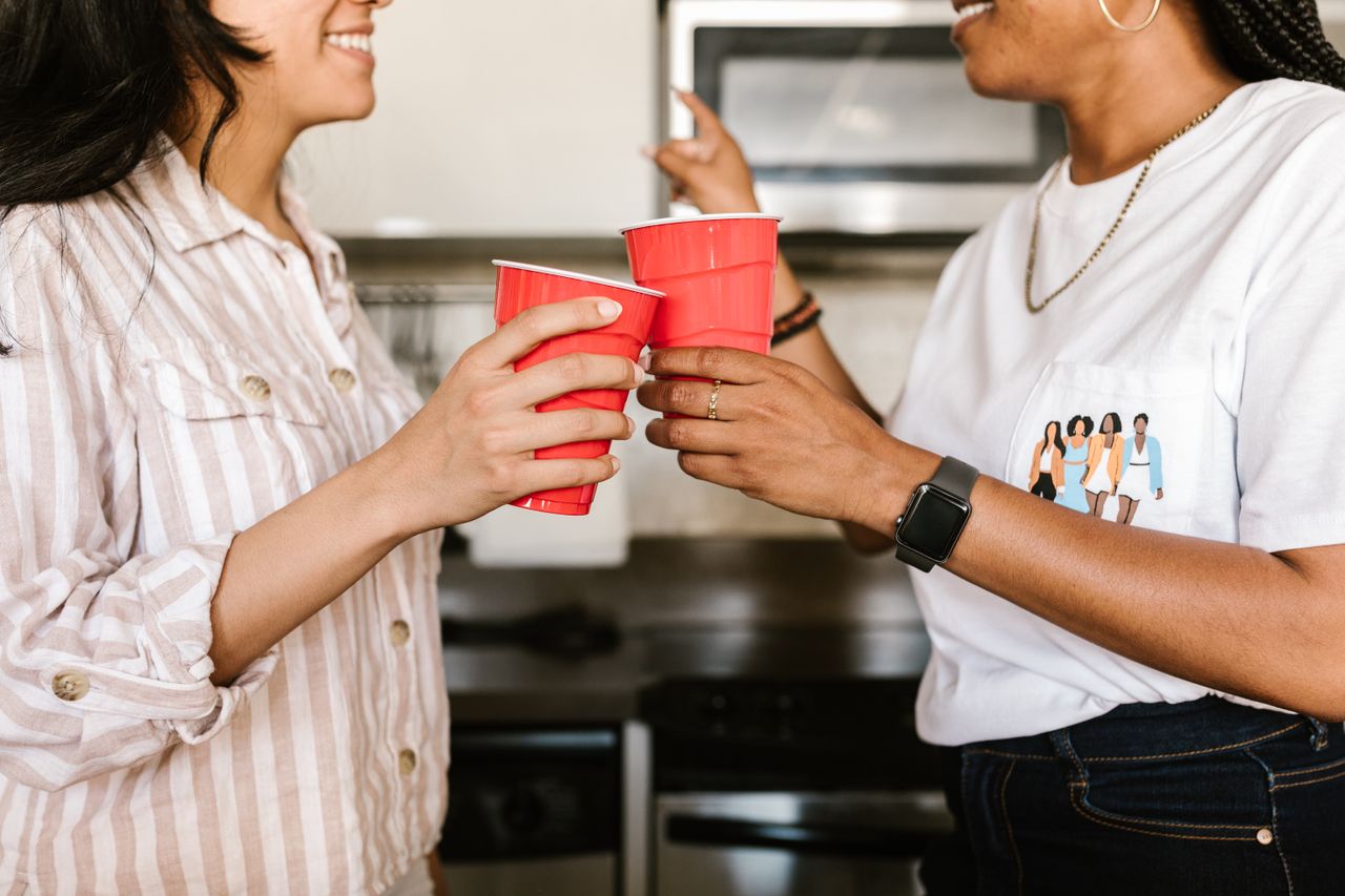 women toasting with red cups in a casual indoor setting enjoying time