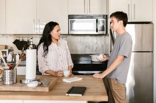 Two people talking across a kitchen counter — photo by RDNE Stock project on Pexels