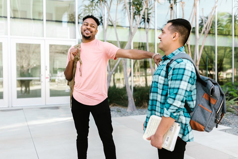 Two college students enjoying a friendly conversation on campus, carrying backpacks.