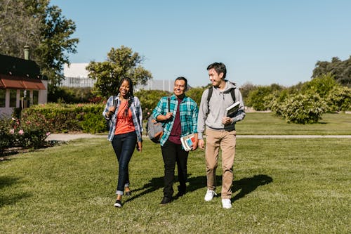 College Students Walking on Grass Field