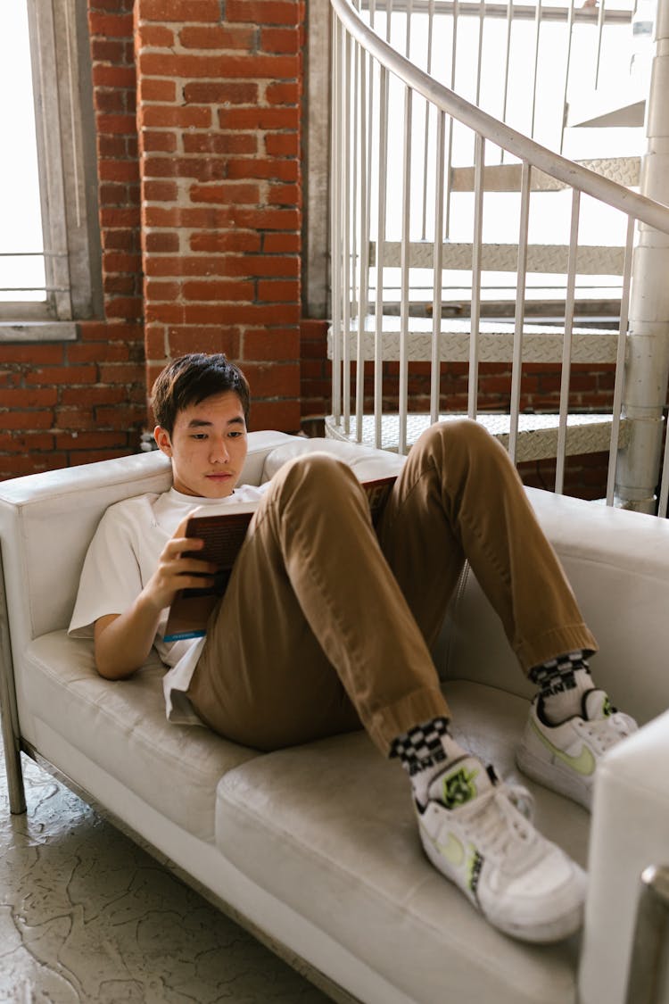 Man Reading A Book White Lying On White Couch