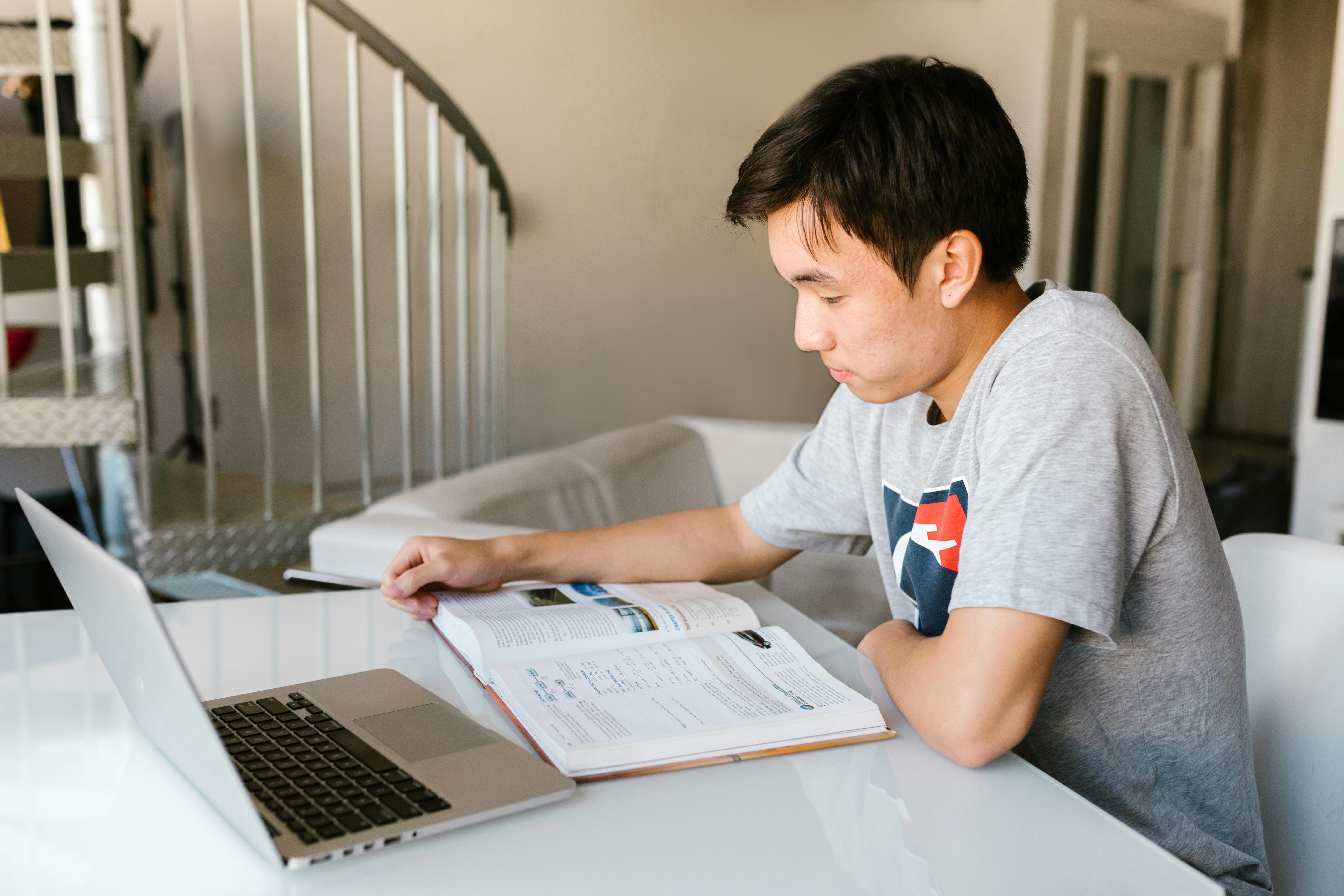 a boy reading a book on white table