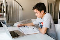A Boy Reading a Book on White Table