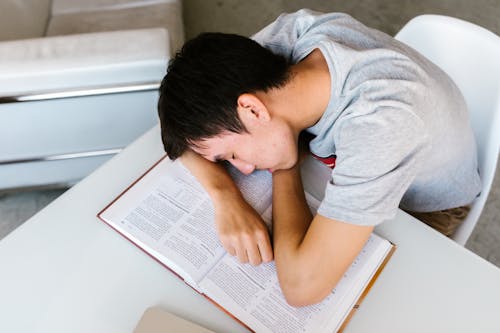 Free Boy Sleeping on an Open Book  on a White Table Stock Photo