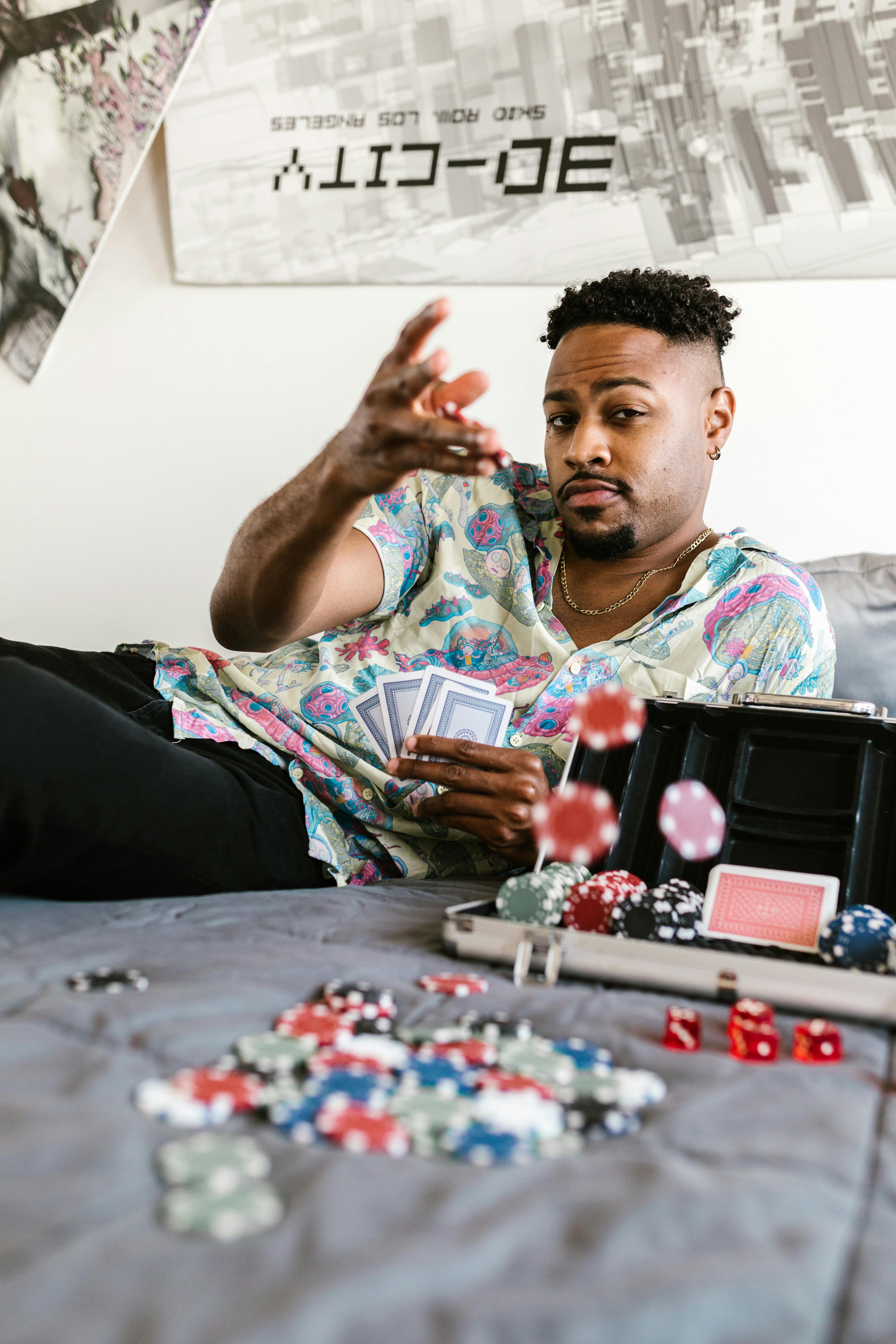 Confident man in casual attire playing poker and tossing cards on bed.