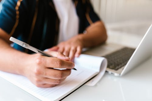 A Person Writing on a Notebook