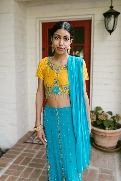 Woman in Blue and Yellow Traditional Dress Standing on a Doorway