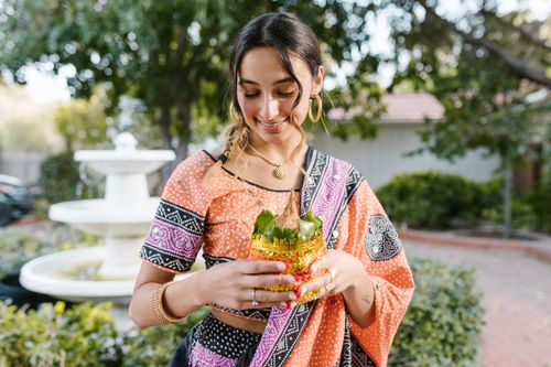 Free A smiling woman in traditional Indian attire holds a decorative offering outdoors. Stock Photo