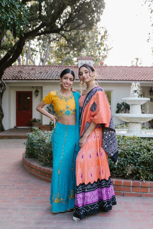 Free Two women in colorful traditional clothing posing outdoors near a fountain. Stock Photo