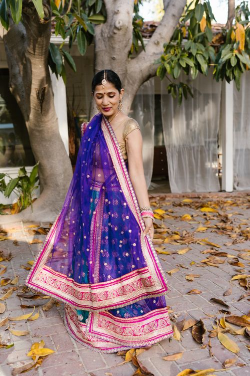 Free A woman in a vibrant purple saree poses elegantly outdoors, showcasing traditional clothing amidst a natural backdrop. Stock Photo