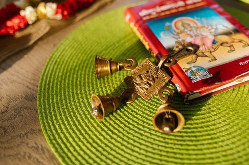 Free Close-up of religious symbols including golden bells and a book on a green placemat. Stock Photo