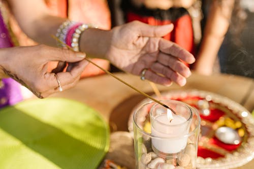 Hands of a Woman Lighting Stick on a White Candle