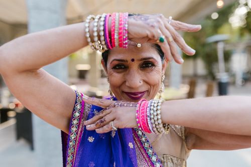Free Senior woman smiling and posing in vibrant traditional Indian clothing with bangles and henna design. Stock Photo