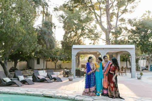Free Four women in colorful traditional attire standing by a poolside with trees in the background. Stock Photo