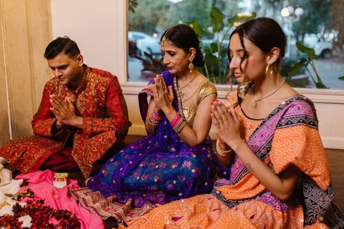 Free A family sitting indoors celebrating Diwali in colorful traditional clothing, hands in prayer. Stock Photo