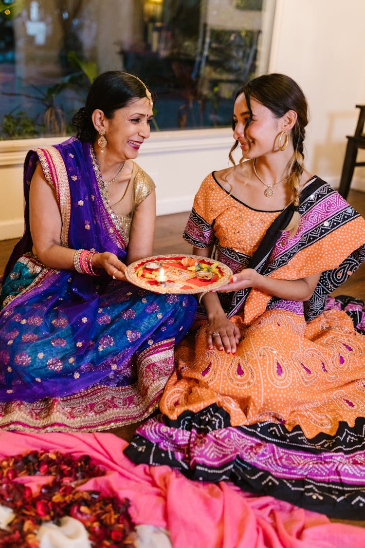 Two Women In Traditional Clothing Holding Puja Thali