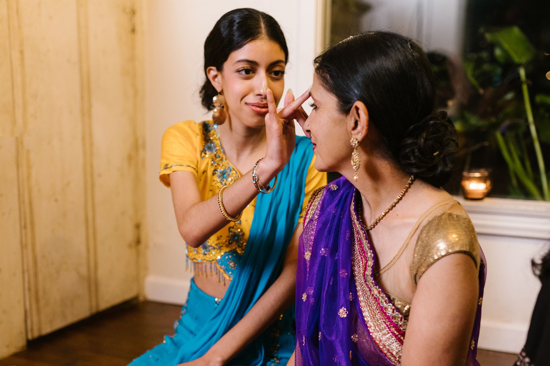 A mother and daughter bond while wearing vibrant sarees, celebrating cultural traditions.