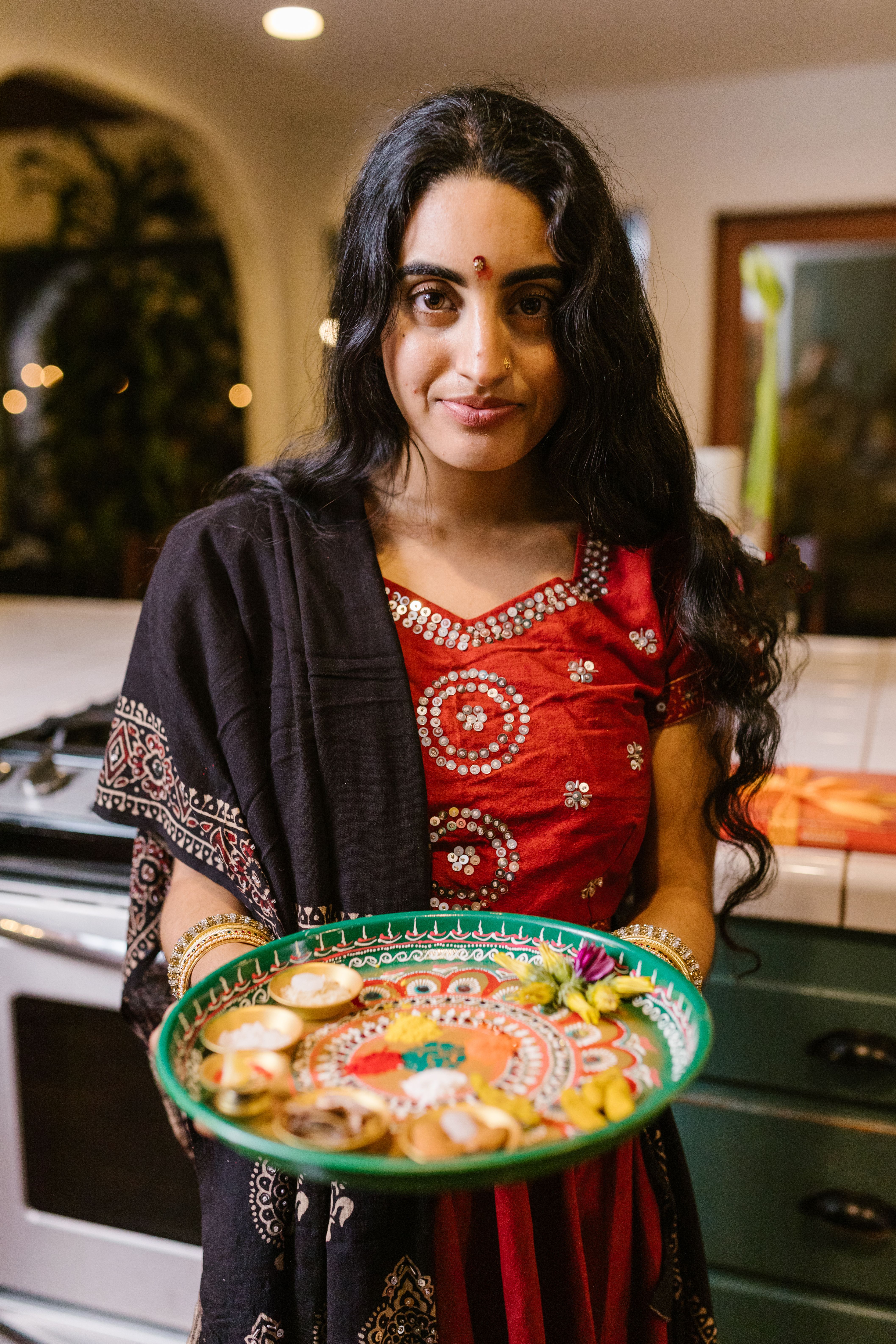 Woman in traditional attire holding a decorated tray for Diwali celebration.