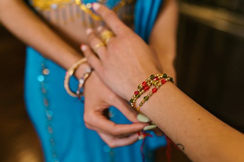 Free A Person Wearing Gold and Red Bracelets Stock Photo