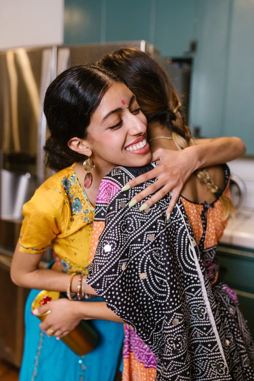 Free Two women warmly hugging in vibrant Indian sarees at home, radiating happiness. Stock Photo