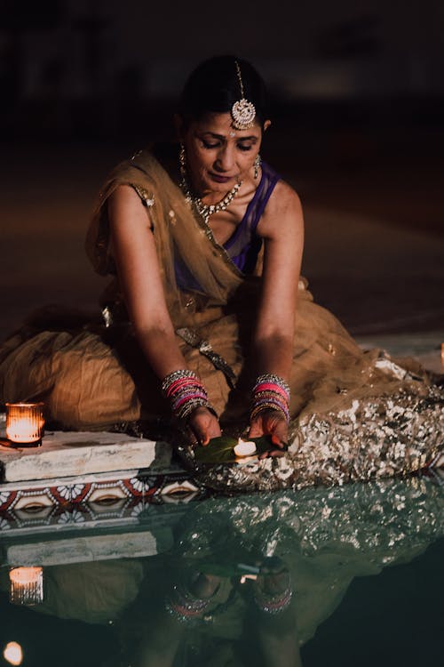 Woman Putting Flowers on Water at Diwali Celebration