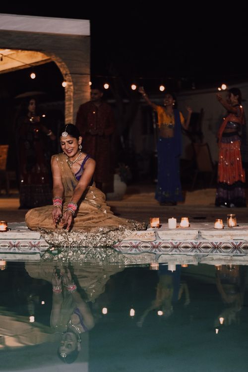 Free An Indian woman in traditional attire celebrates a festival by a candlelit poolside at night. Stock Photo